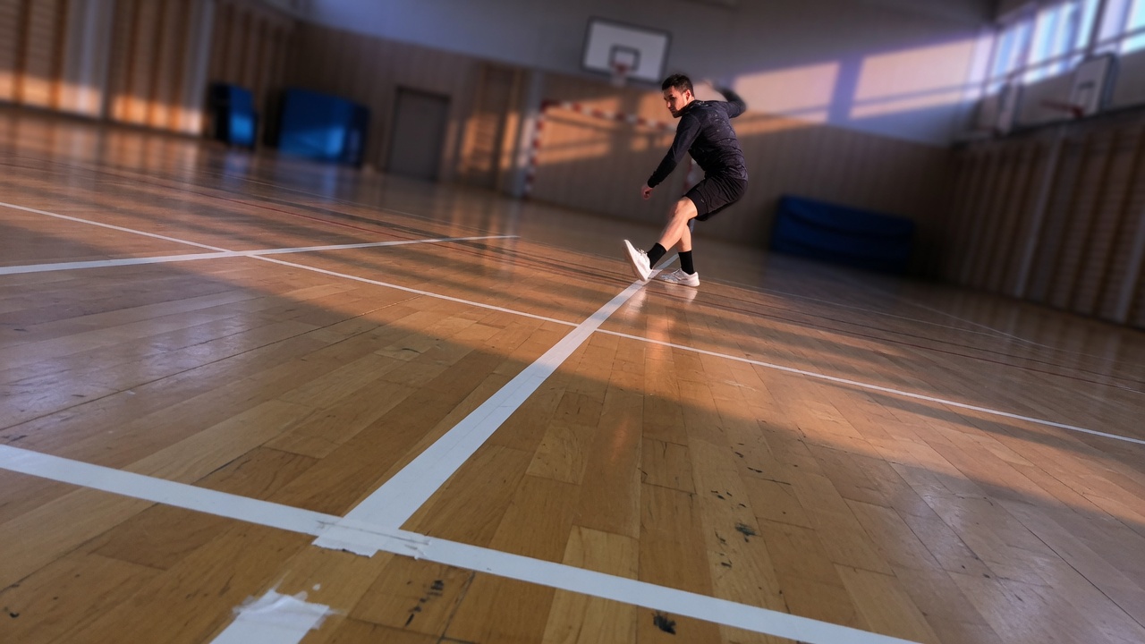 Low phone-level view of an athlete reaching a white tape line with one foot