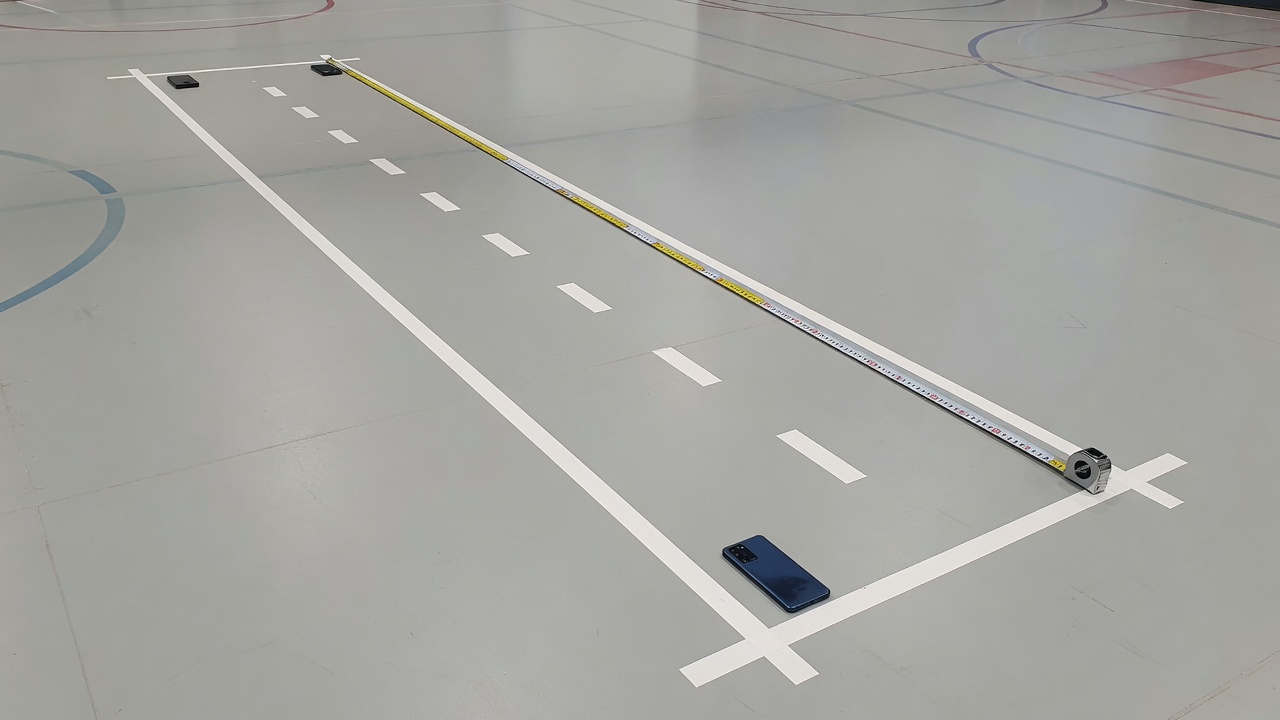 Gym floor with a steel tape along a marked shuttle lane and phones at each end